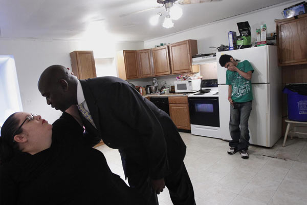 Devin Simpson (R) laughs in the background as his mother Donna Simpson kisses her partner, Phillippe Gouamba, before he leaves for work at their home in Old Bridge, New Jersey June 8, 2010. [China Daily/Agencies]