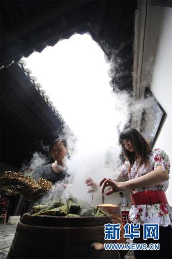 Two girls in Zigui pick out Zongzi from a steamer during their celebration of the Dragon Boat Festival on Thursday, June 10, 2010. The festival, falling on the fifth day of the fifth month of the Chinese lunar calendar, is for people to remember Qu Yuan, a patriotic poet more than 2,000 years ago. Zigui, a county in central China's Hubei province, is thought to be the poet's hometown. [Hao Tongqian/Xinhua]