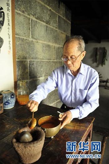 An old man in Zigui is producing realgar wine during the celebration of the Dragon Boat Festival on Thursday, June 10, 2010. People usually drink realgar wine during the festival. [Hao Tongqian/Xinhua]