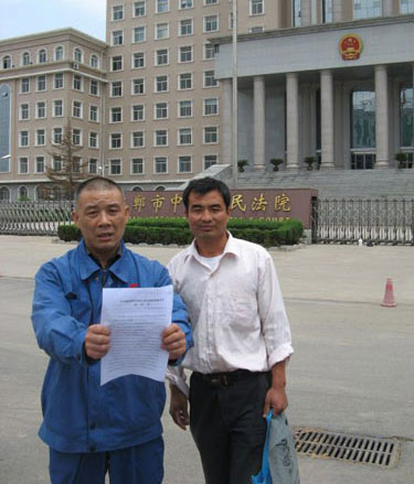 Liu Junhai (L) holds a court order about compensation. [Photo/yzdsb.com.cn]
