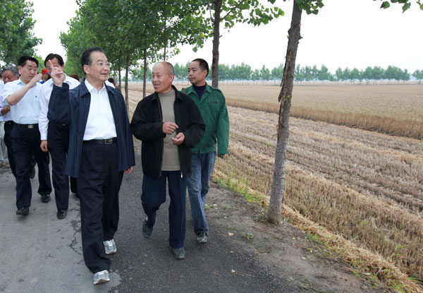 Chinese Premier Wen Jiabao talks with a village official as they walk along a country road in Poliwang village, in Changge city, Central China's Henan province, on Wednesday June 9, 2010. Wen spent Wednesday and Thursday inspecting the wheat harvest in Henan, visiting farmers' families and grain depots. [Photo/Xinhua] 