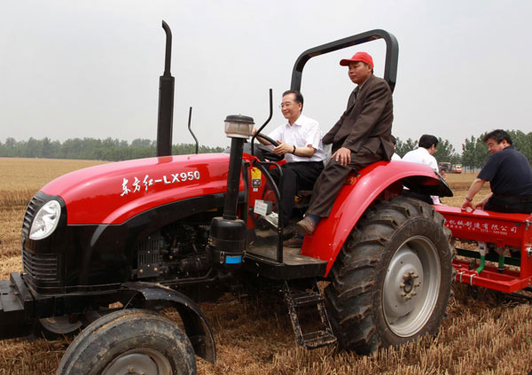 Chinese Premier Wen Jiabao drives a 'Dongfanghong' tractor to help farmers sow corn seeds in Xuchang county, Central China's Henan province, on Wednesday. [Xinhua]