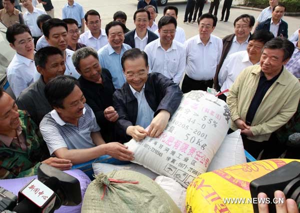 Chinese Premier Wen Jiabao (C) asks farmers about the output, price and purchase of wheat at the entrance of Xinxing National Grain Reserve in Xuchang, central China's Henan Province, June 10, 2010. [Xinhua]