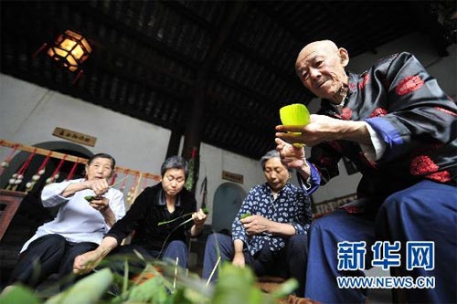 Residents in Zigui make Zongzi (a pyramid-shaped dumpling made of glutinous rice wrapped in bamboo leaves) during their celebration of the Dragon Boat Festival on Thursday, June 10, 2010. Eating Zongzi is a traditional way to celebrate the festival. [Photo: Xinhua/Hao Tongqian]