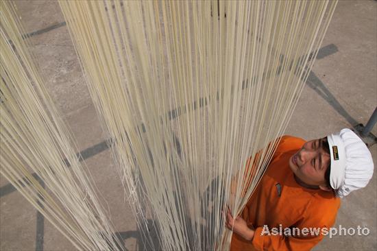 A worker makes fine dry noodles in Yigou village, Tangyin county of Henan province, June 6, 2010. Local pastry cooks can turn chopstick-thin dough into a 200-meter long hollow noodle as thin as a strand of hair. The unique skill is handed down through generations in the village and is the county's intangible culture heritage. [Photo/Asianewsphoto] 