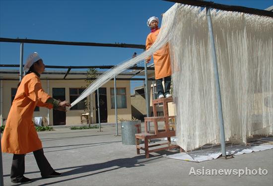 Pastry cooks hang up hollow dry noodles and give it a thorough airing in Yigou village, Tangyin county of Henan province, June 6, 2010. [Photo/Asianewsphoto] 