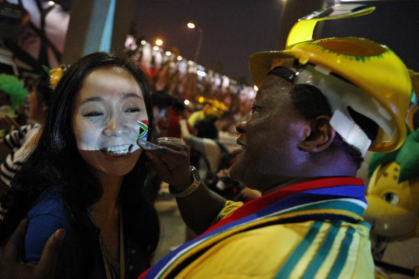 Vika Khumalo (R), South Africa's consul general to Shanghai, paints for a Chinese soccer fan during the ceremony to celebrate the opening of the 2010 FIFA World Cup in South Africa, in the South Africa Pavilion, in Shanghai, east China, June 11, 2010. (Xinhua/Shen Bohan)