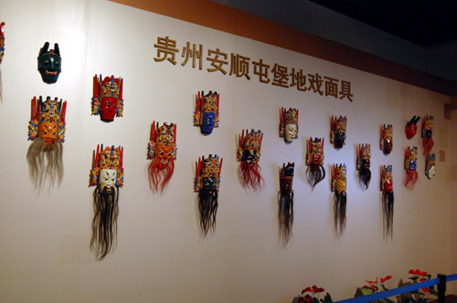 Traditional Chinese opera masks line one of the walls in the exhibit. A film is also displayed nearby, showing examples of opera performances. [Courtney Price/China.org.cn]