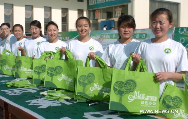 Volunteers of the Institution Energy-saving Week send out recyclable shopping bags to the public in Hohhot, capital of north China's Inner Mongolia Autonomous Region, June 12, 2010. The 2010 Inner Mongolia Institution Energy-saving Week was launched on Saturday. In the following week, institutions in Inner Mongolia will advocate green office and low-carbon life with a series of activities like promoting green traffic, boycotting excessive packaging and experiencing energy-lack life. [Xinhua]
