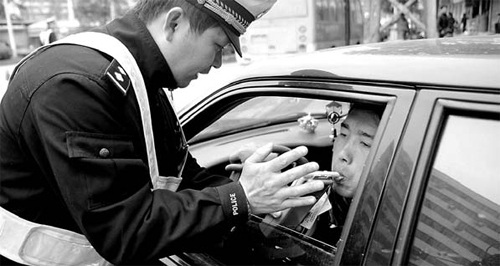A driver blows into a breathalyzer for a police officer in this file photo from Hubei Province.
