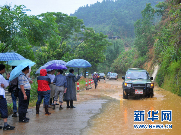 Rescue vehicles drive by a muddy road where 24 people are missing after landslides triggered by heavy rains and swept away two vehicles carrying a total of 31 people in Nanping, Fujiang Province, June 14, 2010. Seven people have been rescued. [Xinhua]