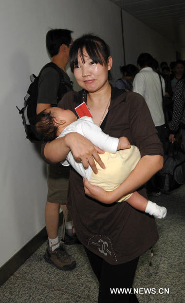 A woman holds her baby upon arrival at the Urumqi airport, Xinjiang Uygur autonomous region from turbulent Kyrgyzstan by China Southern Airlines (CSA) chartered flight, June 15, 2010.