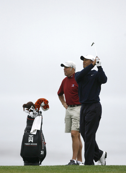 Tiger Woods (R) of the U.S. hits his approach shot on the eighth hole as his caddie Steve Williams looks on during a practice round for the U.S. Open Golf Championship in Pebble Beach, California June 14, 2010.