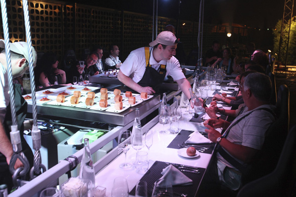 A chef serves guests seated around a table at an event venue known as 'Dinner in the Sky', before the table is lifted by a crane, in Beirut June 12, 2010.