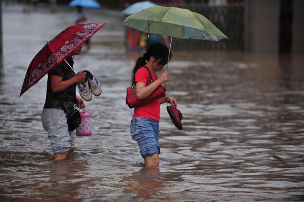 People wade through the flooded street in Nanning, capital of Southwest China's Guangxi Zhuang autonomous region, June 15, 2010. A fresh spell of heavy rains has pounded Guangxi since June 14, triggering floods in some regions of Guangxi.[Photo/Xinhua]