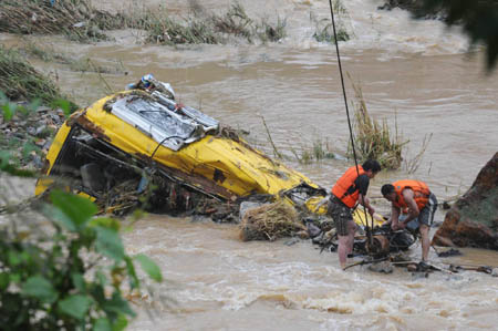 Rescuers drag out a passenger vehicle engulfed in the river by the landslide in Nanping, Fujian Province, June 15, 2010.[Photo/Xinhua]