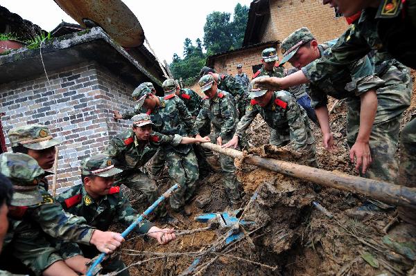 Armed police search for the missing at the site of rainstorm-triggered landslide in Cangwu County of southwest China's Guangxi Zhuang Autonomous Region, June 16, 2010. 