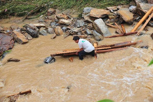 A man tries to take back wood pieces in flood in Cangwu County of southwest China's Guangxi Zhuang Autonomous Region, June 16, 2010. [Xinhua]