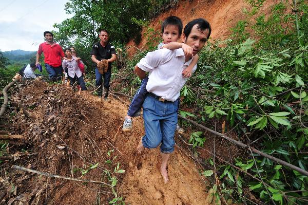 Local residents walk on the road covered with mud and rock after flood in Cangwu County of southwest China's Guangxi Zhuang Autonomous Region, June 16, 2010. [Xinhua]