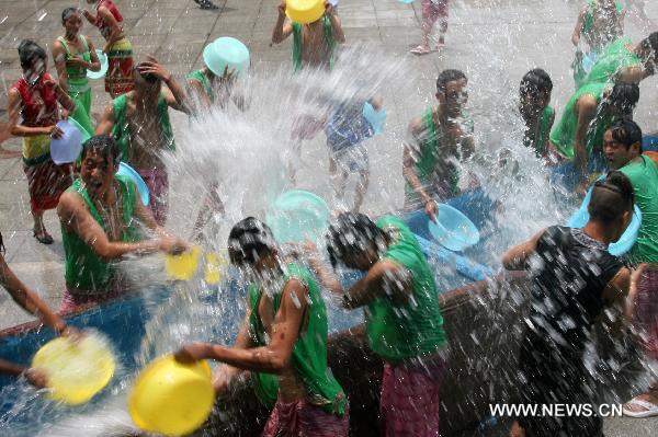 Girls and lads of Dai ethnic group indulge themselves in furious fun of splashing water together with tourists, inside the Nine Pinnacle Tower Happy Land of Chinese Folk Custom, in Jinan, east China's Shandong Province, June 16, 2010. Series of funny activities including splashing water, contest of eating Zongzi, etc, are held inside the happy land to enable the tourists enjoying the saturnalia of coolness under the sultry summer season. [Xinhua/Lv Chuanquan]