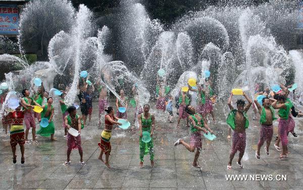 Girls and lads of Dai ethnic group indulge themselves in furious fun of splashing water together with tourists, inside the Nine Pinnacle Tower Happy Land of Chinese Folk Custom, in Jinan, east China's Shandong Province, June 16, 2010. Series of funny activities including splashing water, contest of eating Zongzi, etc, are held inside the happy land to enable the tourists enjoying the saturnalia of coolness under the sultry summer season. [Xinhua/Lv Chuanquan] 