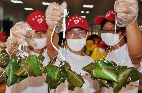 Three students of the Biological and Food Engineering School of the Changshu Institute of Science and Technology show up their hand-made Zongzi, as some 150 students and teachers take part in a commonweal activity of wrapping up the Love Hearts Zongzi, a traditional Chinese snack of pyramid-shaped dumplings made of glutinous rice wrapped in bamboo and or reed leaves, in Changshu, Jiangsu Province, June 2, 2010.