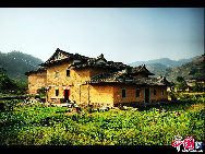 Photo taken on June. 6, 2010 shows the Dadi Tulou, earth buildings in Chinese, in Hua'an County, southeast China's Fujian Province. Built on a base of stone, the thick walls of Tulou were packed with dirt and fortified with wood or bamboo internally. The architectural arts of the Fujian Tulou can be traced back nearly 1,000 years, and their design incorporates the tradition of fengshui (favorable siting within the environment). [Photo by Zhou Yunjie]