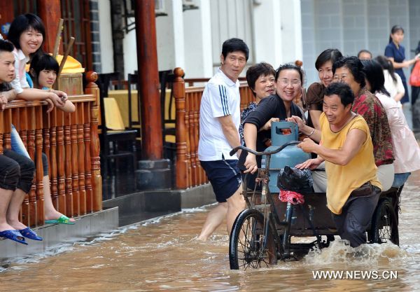 Women citizens sit in a tricycle on a flooded street in Guilin, southwest China&apos;s Guangxi Zhuang Autonomous Region, June 17, 2010. Heavy rainfalls caused flood in Guilin on Thursday. [Xinhua] 