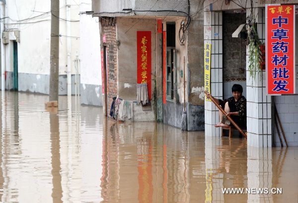 A woman sits beside a flooded street in Guilin, southwest China&apos;s Guangxi Zhuang Autonomous Region, June 17, 2010. Heavy rainfalls caused flood in Guilin on Thursday. [Xinhua] 