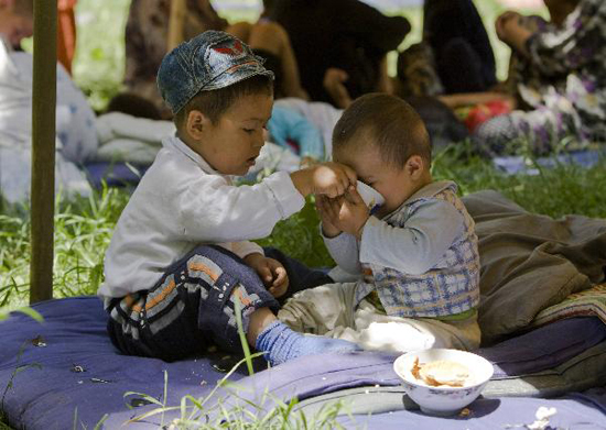 Children eat at a refugee camp for ethnic Uzbeks fleeing from clashes in Jalalabad Region in Kara-Su, near the border with Kyrgyzstan some 400 km (249 miles) east of Tashkent June 16, 2010. [Xinhua photo]