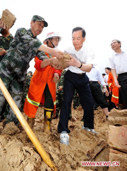 Chinese Premier Wen Jiabao (front R) cleans ruins with rescuers in Shuangshang village in Cangwu County of southwest China's Guangxi Zhuang Autonomous Region, June 20, 2010. Wen Jiabao inspected flood-affected area in Guangxi from June 19 to 20. (Xinhua