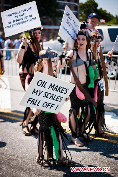 People hold placards to protest against the oil spill pollution caused by the British Petroleum in the Gulf of Mexico during the annual Mermaid Parade in Coney Island, New York, the United States, June 19, 2010. The Mermaid Parade, characterized by participants dressed in hand-made costumes as Mermaids and various sea creatures, celebrates the sand, the sea, the salt air and the beginning of summer. [Xinhua] 