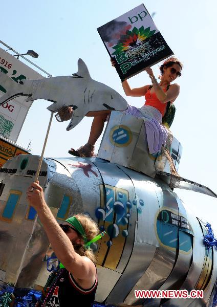 People hold placards to protest against the oil spill pollution caused by the British Petroleum in the Gulf of Mexico during the annual Mermaid Parade in Coney Island, New York, the United States, June 19, 2010. The Mermaid Parade, characterized by participants dressed in hand-made costumes as Mermaids and various sea creatures, celebrates the sand, the sea, the salt air and the beginning of summer. [Xinhua]