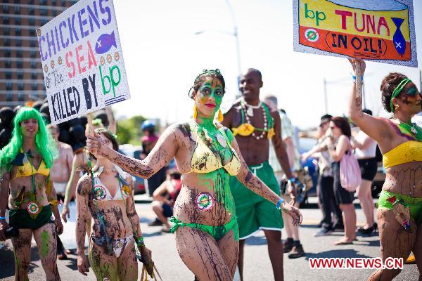 People hold placards to protest against the oil spill pollution caused by the British Petroleum in the Gulf of Mexico during the annual Mermaid Parade in Coney Island, New York, the United States, June 19, 2010. The Mermaid Parade, characterized by participants dressed in hand-made costumes as Mermaids and various sea creatures, celebrates the sand, the sea, the salt air and the beginning of summer. [Xinhua]