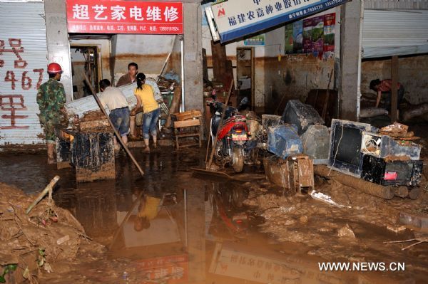 Local people clear stores damaged by flood at Taining County, southeast China&apos;s Fujian Province, June 19, 2010.