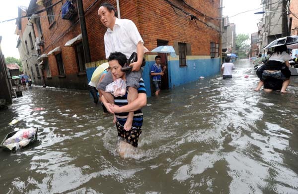 Residents wade through a flooded street in Shizikou Village in Nanchang, east China's Jiangxi Province June 19, 2010. 