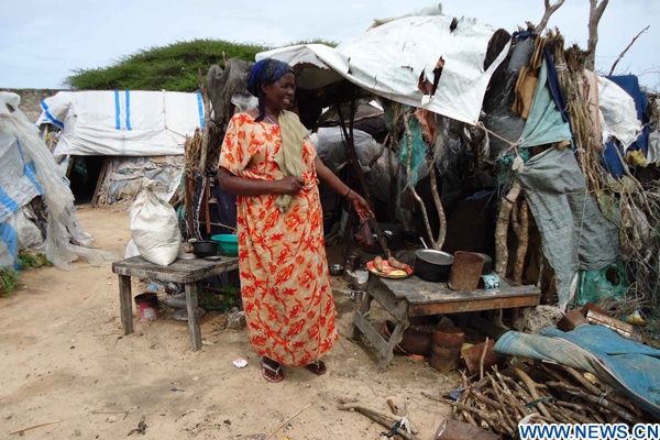 A woman stands outside a makeshift tent at a refugee camp in the Somali capital Mogadishu June 20, 2010. (Xinhua/Ismail Warsameh)