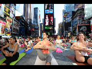 People gather to practice yoga on the morning of the summer solstice in New York's Times Square June 21, 2010. The eighth annual 'Solstice in Times Square' event on Monday brought out thousands of participants to celebrate the year's longest day. [Xinhua]