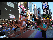 People gather to practice yoga on the morning of the summer solstice in New York's Times Square June 21, 2010. [Xinhua]