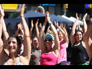 People gather to practice yoga on the morning of the summer solstice in New York's Times Square June 21, 2010. [Xinhua]