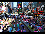 People gather to practice yoga on the morning of the summer solstice in New York's Times Square June 21, 2010. [Xinhua]