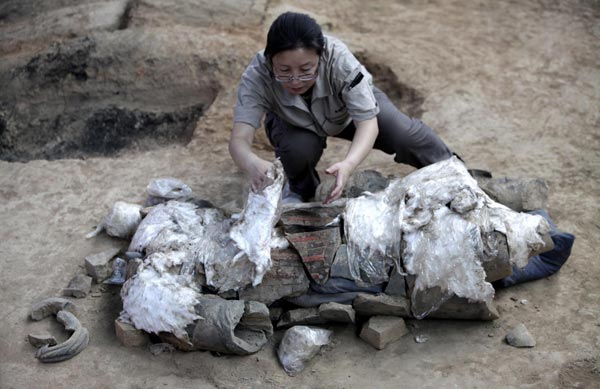 Archaeologist Xu Weihong covers the coloured battle suit of a newly found terracotta warrior at the excavation site inside the No 1 pit of the Museum of Qin Terracotta Warriors and Horses, on the outskirts of Xi&apos;an, Shaanxi province June 21, 2010. [China Daily/Agencies] 