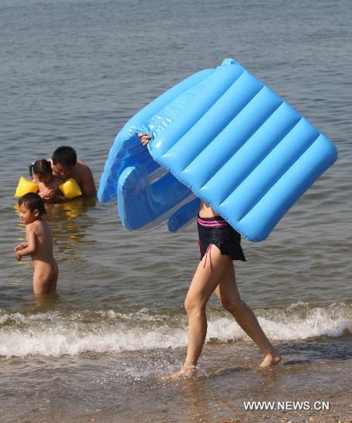 A girl carries an air bed at a beach in Yantai, east China's Shandong Province, June 21, 2010.