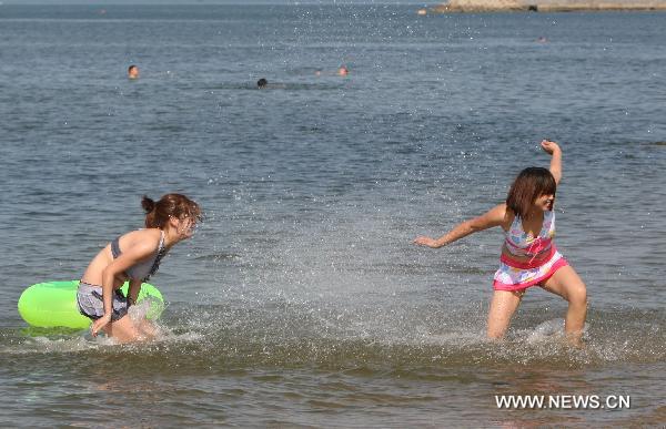 Two girls play in the sea to cool themselves off in Yantai, east China's Shandong Province, June 21, 2010. 