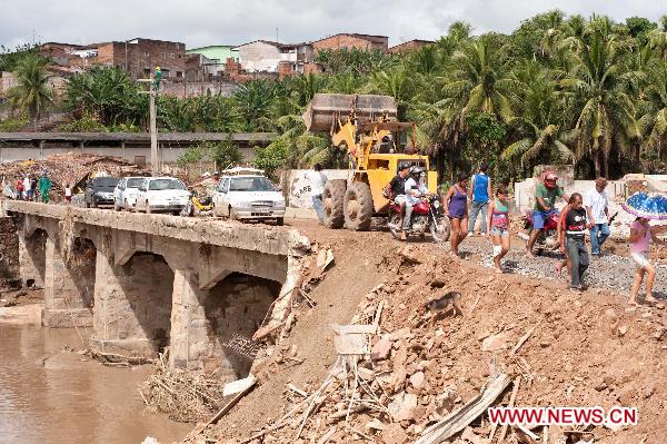 People walk on a damaged road caused by overflowing water in the northeastern part of Brazil, June 22, 2010. Raging floods in northeastern Brazil have killed at least 41 people and left as many as 1,000 missing, officials said Tuesday. [Agencia Estado/Xinhua]