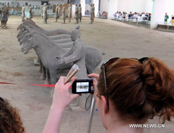 A tourist takes photos of the unearthed terracotta warriors and horses at No 1 pit of the Museum of Qin Shihuang Terracotta Warriors and Horses in Xi'an, capital of northwest China's Shaanxi Province, June 22, 2010. The number of tourists reached 10,000 per day recently, which increased about 24 percent comparing with the same period last year, although the heat wave swept over Xi'an recently. [Xinhua/Jiao Weiping]