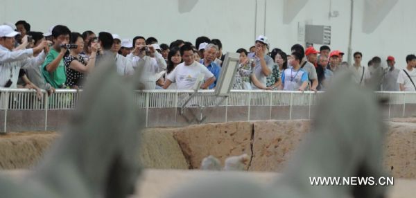 Tourists take a look at the unearthed terracotta warriors at No 1 pit of the Museum of Qin Shihuang Terracotta Warriors and Horses in Xi'an, capital of northwest China's Shaanxi Province, June 22, 2010. The number of tourists reached 10,000 per day recently, which increased about 24 percent comparing with the same period last year, although the heat wave swept over Xi'an recently. [Xinhua/Jiao Weiping]