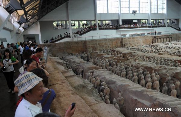 Tourists take a look at the unearthed terracotta warriors at No 1 pit of the Museum of Qin Shihuang Terracotta Warriors and Horses in Xi'an, capital of northwest China's Shaanxi Province, June 22, 2010. The number of tourists reached 10,000 per day recently, which increased about 24 percent comparing with the same period last year, although the heat wave swept over Xi'an recently. [Xinhua/Jiao Weiping] 