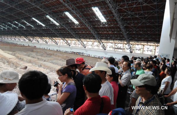 Tourists take a look at the unearthed terracotta warriors at No 1 pit of the Museum of Qin Shihuang Terracotta Warriors and Horses in Xi'an, capital of northwest China's Shaanxi Province, June 22, 2010. The number of tourists reached 10,000 per day recently, which increased about 24 percent comparing with the same period last year, although the heat wave swept over Xi'an recently. (Xinhua/Jiao Weiping) 