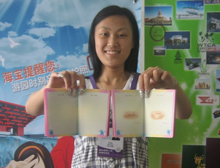 A staffer at an officially licensed Expo store inside the Expo Park displays the new (left) and old (right) Expo passports Monday. Photo: Ni Dandan 